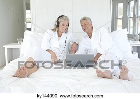 Couple in bathrobe using laptop in bed View Large Photo Image Stock Image - Couple in bathrobe using laptop in bed. Fotosearch