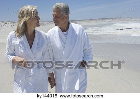 Stock Photography - Couple in bathrobe walking on the beach. Fotosearch
