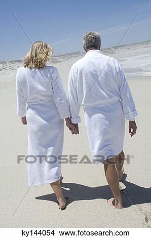 Couple in bathrobe walking on the beach, rear view View Large Photo Image Picture - Couple in bathrobe walking on the beach, rear view. Fotosearch