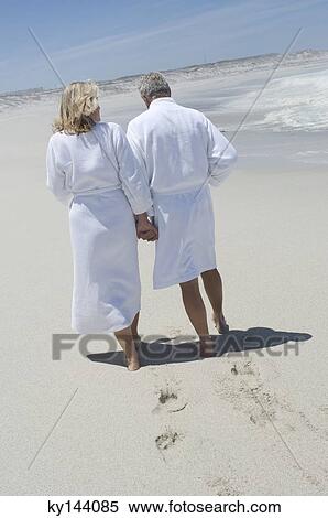 Couple in bathrobe walking on the beach, rear view View Large Photo Image Stock Photography - Couple in bathrobe walking on the beach, rear view. Fotosearch