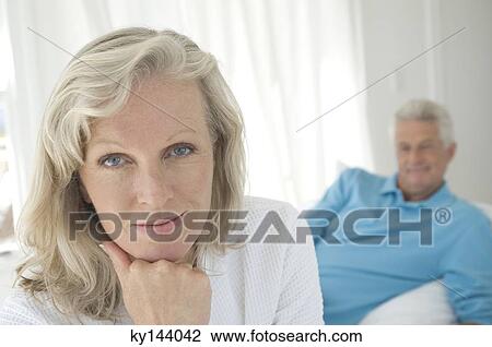 Couple in bedroom, woman looking at camera, man lying in background View Large Photo Image Stock Image - Couple in bedroom, woman looking at camera, man lying in background. Fotosearch