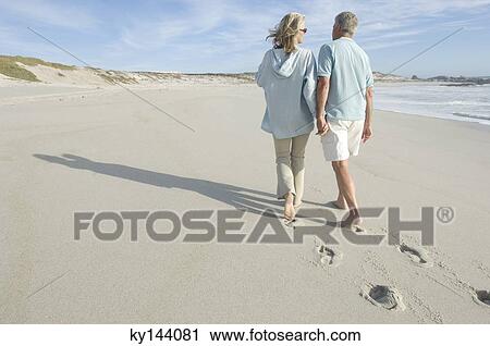 Couple walking on the beach, rear view View Large Photo Image Stock Image - Couple walking on the beach, rear view. Fotosearch