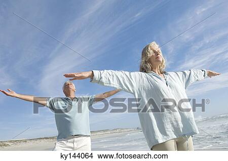 Couple with arms out on the beach, eyes closed View Large Photo Image Picture - Couple with arms out on the beach, eyes closed. Fotosearch