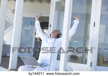 Man listening to music with laptop, arms in the air View Large Photo Image Stock Image - Man listening to music with laptop, arms in the air. Fotosearch