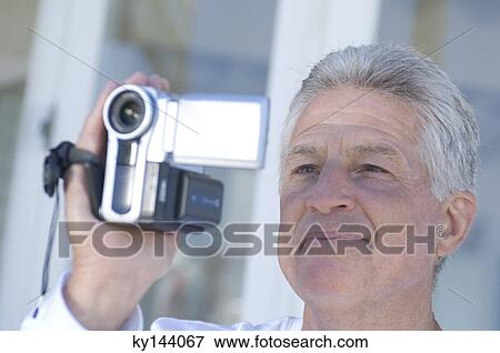 Man using camcorder View Large Photo Image Stock Photo - Man using camcorder. Fotosearch