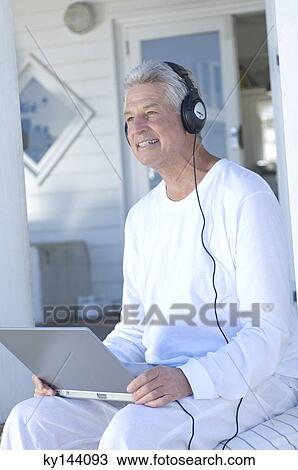 Man with headphones using laptop View Large Photo Image Stock Image - Man with headphones using laptop. Fotosearch