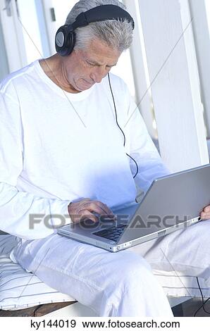 Stock Photo - Man with headphones using laptop. Fotosearch