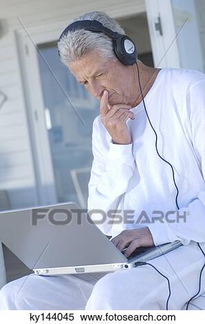 Man with headphones using laptop View Large Photo Image Stock Photography - Man with headphones using laptop. Fotosearch