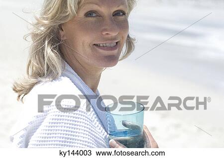 Portrait of smiling woman on the beach, holding glass of water View Large Photo Image Stock Image - Portrait of smiling woman on the beach, holding glass of water. Fotosearch