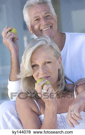 Stock Photo - Smiling couple eating apples. Fotosearch