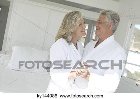 Smiling couple in bathrobe embracing inbedroom View Large Photo Image Stock Photograph - Smiling couple in bathrobe embracing inbedroom. Fotosearch