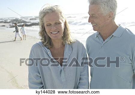 Smiling couple on the beach, another couple in background View Large Photo Image Stock Photo - Smiling couple on the beach, another couple in background. Fotosearch