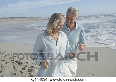 Smiling couple running on the beach View Large Photo Image Picture - Smiling couple running on the beach. Fotosearch