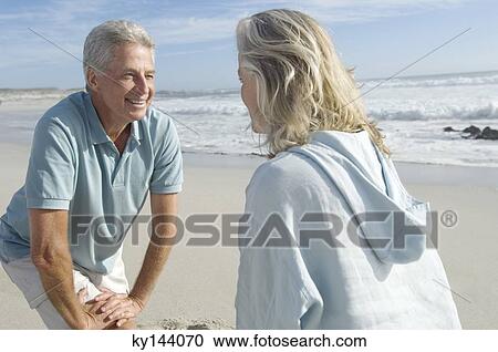 Stock Image - Smiling couple stretching on the beach. Fotosearch