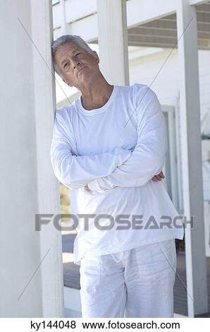 Stock Photo - Thinking man with arms crossed, resting his head on terrace beam. Fotosearch