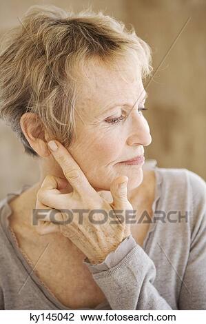Stock Image - Portrait of senior woman touching her ear. Fotosearch