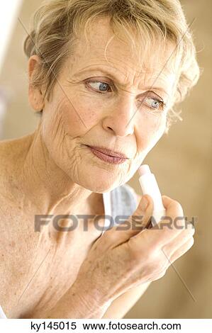 Stock Photography - Portrait of senior woman using lipstick. Fotosearch