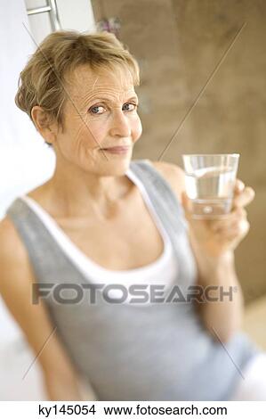 Senior woman holding glass of water View Large Photo Image Picture - Senior woman holding glass of water. Fotosearch
