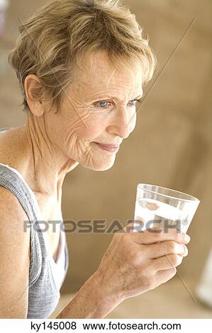 Senior woman holding glass of water View Large Photo Image Stock Photo - Senior woman holding glass of water. Fotosearch