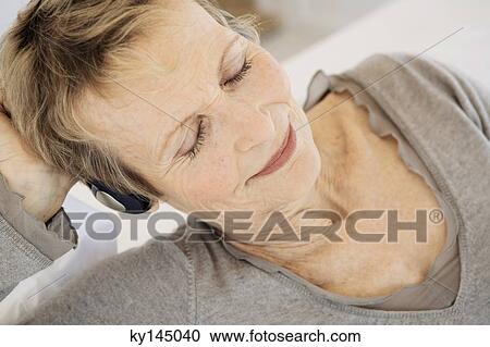 Stock Image - Senior woman listening to music with headphones. Fotosearch