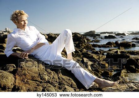 Senior woman lying on seaside rocks View Large Photo Image Stock Image - Senior woman lying on seaside rocks. Fotosearch