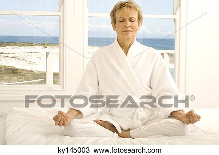 Senior woman sitting cross-legged on bed View Large Photo Image Stock Image - Senior woman sitting cross-legged on bed. Fotosearch