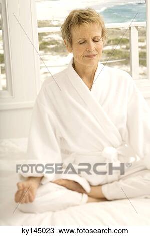 Senior woman sitting cross-legged on bed View Large Photo Image Stock Image - Senior woman sitting cross-legged on bed. Fotosearch