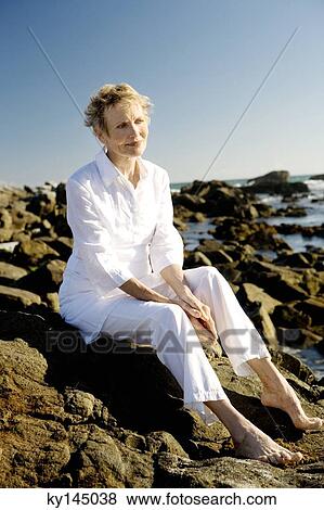 Senior woman sitting on seaside rocks View Large Photo Image Stock Photo - Senior woman sitting on seaside rocks. Fotosearch