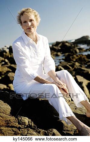 Senior woman sitting on seaside rocks View Large Photo Image Stock Photograph - Senior woman sitting on seaside rocks. Fotosearch
