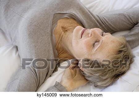 Senior woman sleeping, hands behind head View Large Photo Image Stock Photo - Senior woman sleeping, hands behind head. Fotosearch