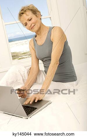 Picture - Senior woman using credit card on internet. Fotosearch