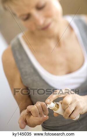 Stock Photography - Senior woman using moisturizer spray. Fotosearch