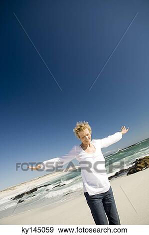 Stock Photo - Senior woman with arms out on the beach. Fotosearch