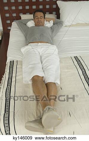 Man lying on a bed, indoors View Large Photo Image Stock Photo - Man lying on a bed, indoors. Fotosearch