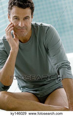 Man sitting indoors, posing for the camera View Large Photo Image Stock Photo - Man sitting indoors, posing for the camera. Fotosearch