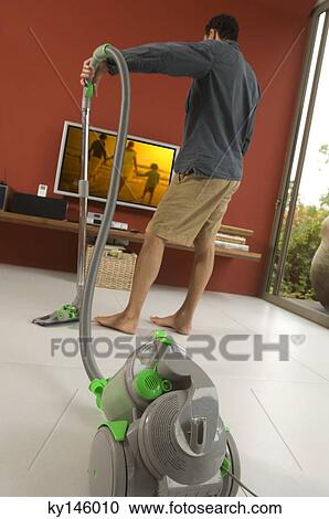 Man vacuuming, indoors View Large Photo Image Stock Image - Man vacuuming, indoors. Fotosearch