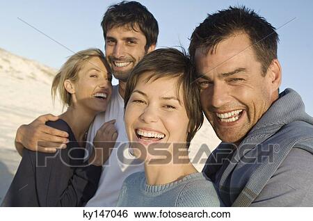 Stock Photograph - 2 smiling couples on the beach. Fotosearch