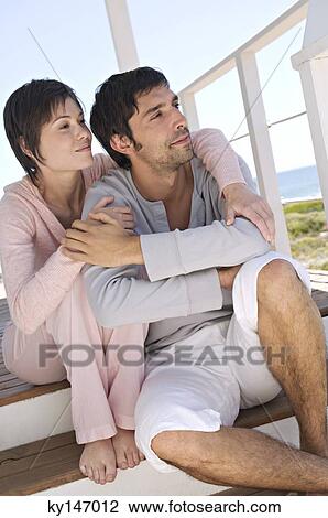 Couble embracing, sitting on wooden terrace View Large Photo Image Stock Image - Couble embracing, sitting on wooden terrace. Fotosearch