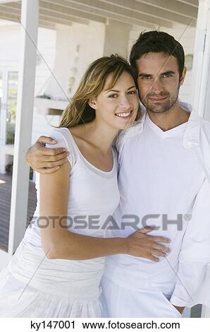 Stock Image - Couple embracing, looking at camera. Fotosearch