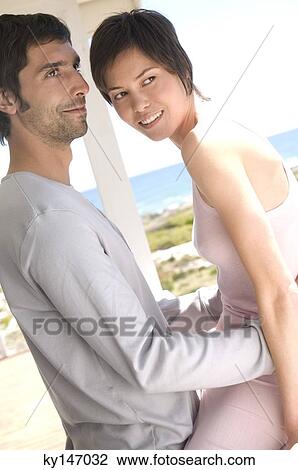 Stock Image - Couple embracing on terrace. Fotosearch