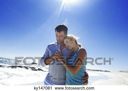 Stock Image - Couple embracing on the beach. Fotosearch