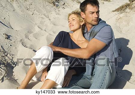 Couple embracing, sitting on the beach View Large Photo Image Stock Image - Couple embracing, sitting on the beach. Fotosearch