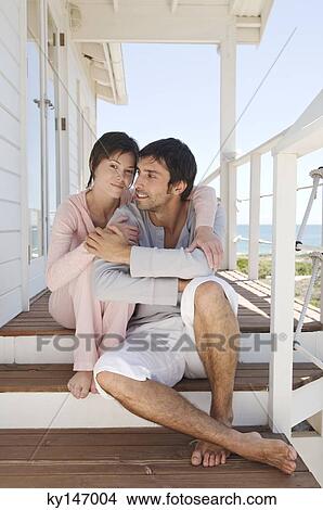 Picture - Couple embracing, sitting on wooden terrace. Fotosearch