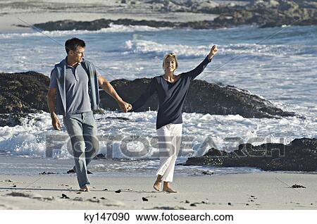Couple holding hands, walking on the beach View Large Photo Image Stock Image - Couple holding hands, walking on the beach. Fotosearch