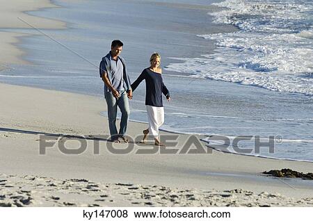 Couple holding hands, walking on the beach View Large Photo Image Stock Photo - Couple holding hands, walking on the beach. Fotosearch