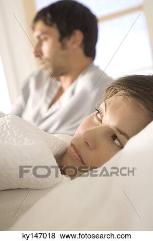 Couple in bed, sulking woman in foreground View Large Photo Image Stock Photo - Couple in bed, sulking woman in foreground. Fotosearch