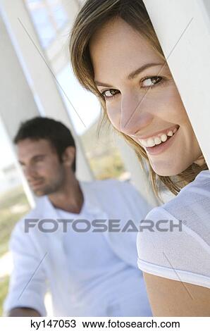 Couple on terrace, woman smiling for the camera in foreground View Large Photo Image Stock Image - Couple on terrace, woman smiling for the camera in foreground. Fotosearch
