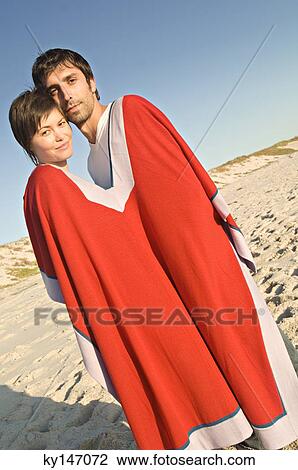 Couple on the beach, sharing a poncho View Large Photo Image Stock Image - Couple on the beach, sharing a poncho. Fotosearch