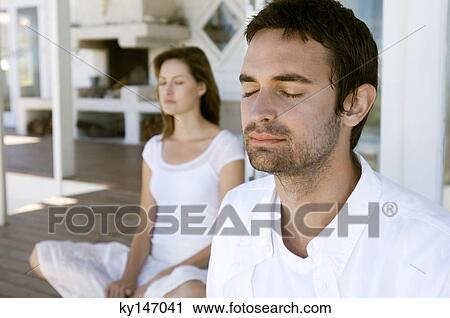 Couple sitting cross-legged on wooden terrace, eyes closed View Large Photo Image Stock Image - Couple sitting cross-legged on wooden terrace, eyes closed. Fotosearch