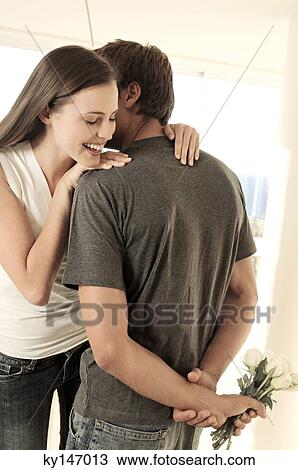 Man hiding bunch of flowers behind his back, facing smiling woman View Large Photo Image Stock Image - Man hiding bunch of flowers behind his back, facing smiling woman. Fotosearch